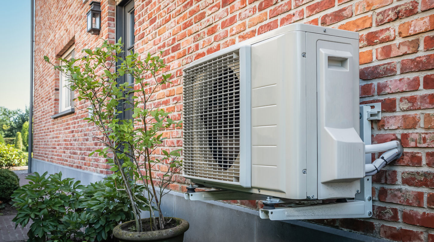 Gros plan sur les ailettes métalliques et le ventilateur d'une unité extérieure de pompe à chaleur moderne