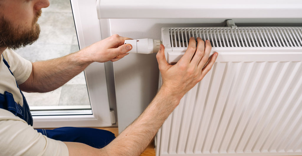Propriétaire consultant une checklist de vérification près de son système de chauffage nouvellement installé dans un sous-sol résidentiel québécois